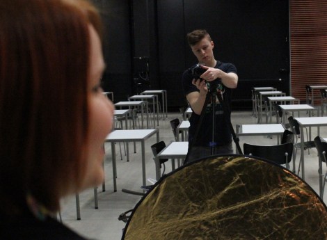 Lari Koponen säätää kameraa ja Roosa Jarkko odottelee kuvaussession alkamista. Larin edessä on reflektori, jokka kasvoihin saadaan lisää valoa ja kullansävyä. Kuva: Antti Pentikäinen.